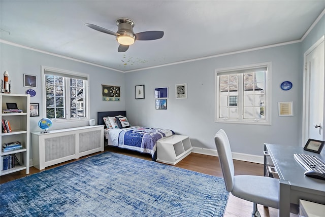 bedroom with a ceiling fan, crown molding, baseboards, and wood finished floors