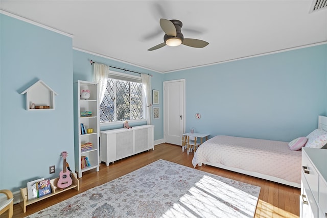 bedroom featuring ceiling fan, wood finished floors, visible vents, radiator, and crown molding