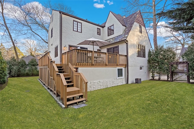 rear view of property featuring a yard, a wooden deck, stairs, and stucco siding