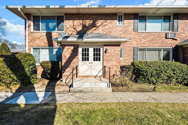 back of house featuring french doors, brick siding, and a wall mounted air conditioner