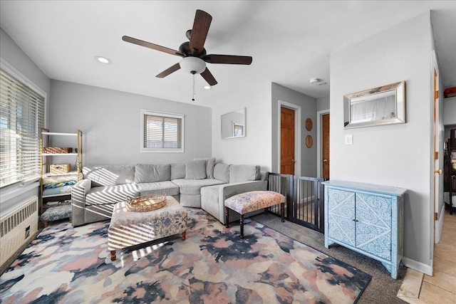 living room featuring baseboards, recessed lighting, a ceiling fan, and radiator