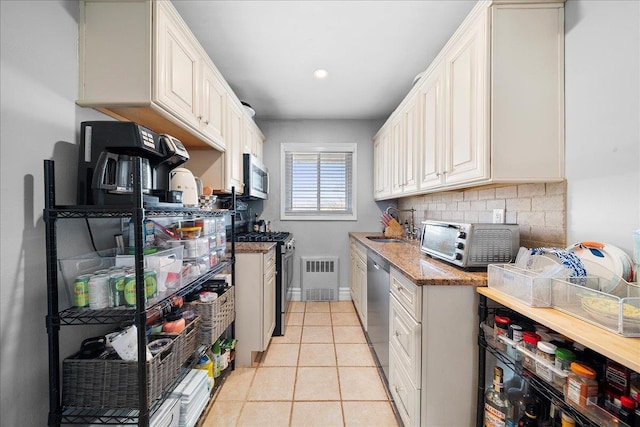 kitchen with light tile patterned floors, appliances with stainless steel finishes, backsplash, and white cabinetry