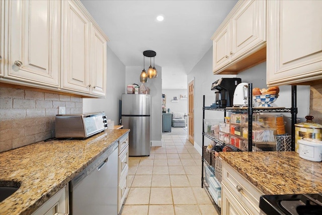 kitchen with light tile patterned floors, hanging light fixtures, appliances with stainless steel finishes, backsplash, and light stone countertops