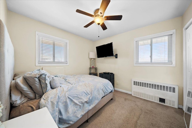 bedroom featuring radiator, multiple windows, baseboards, and light colored carpet