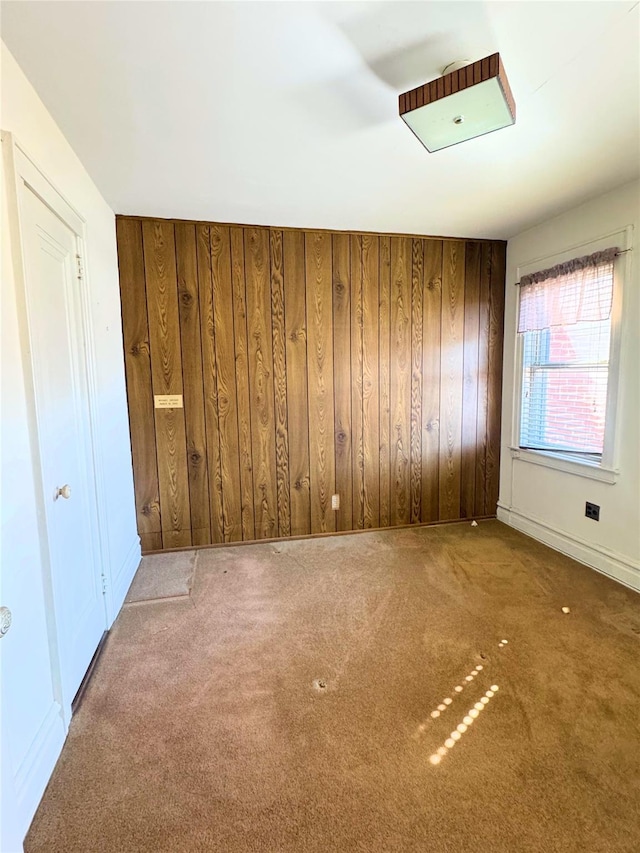 carpeted spare room with wood walls