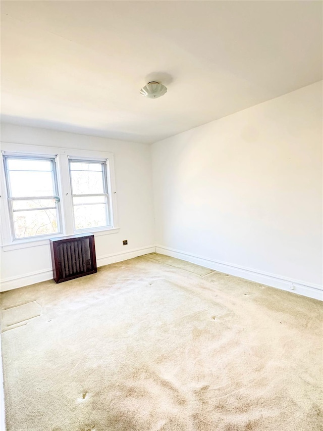 unfurnished room featuring radiator, baseboards, and carpet