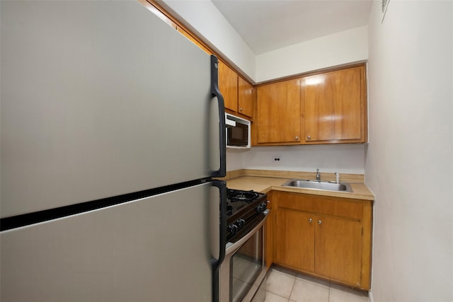 kitchen with black microwave, a sink, light countertops, freestanding refrigerator, and stainless steel gas stove