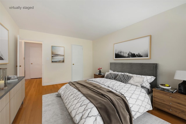 bedroom featuring light wood finished floors and baseboards