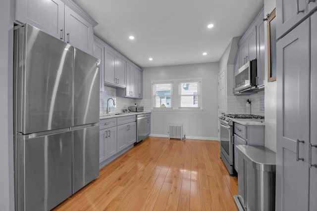 kitchen with light countertops, appliances with stainless steel finishes, radiator heating unit, and gray cabinets