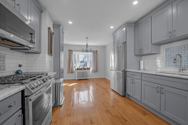 kitchen with radiator, gray cabinets, stainless steel appliances, and a sink