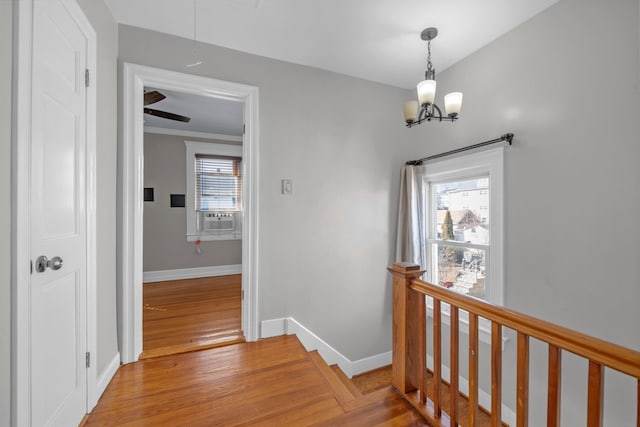 hall with cooling unit, wood finished floors, an upstairs landing, baseboards, and attic access