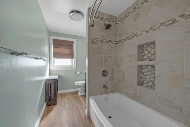 full bath featuring wood finished floors, shower / tub combination, toilet, and baseboards