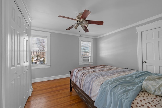 bedroom featuring crown molding, a closet, ceiling fan, wood finished floors, and baseboards