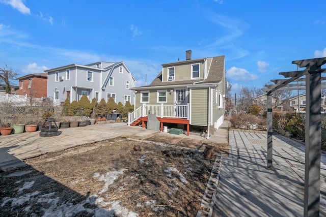 back of property featuring a chimney, a shingled roof, fence, a pergola, and a residential view