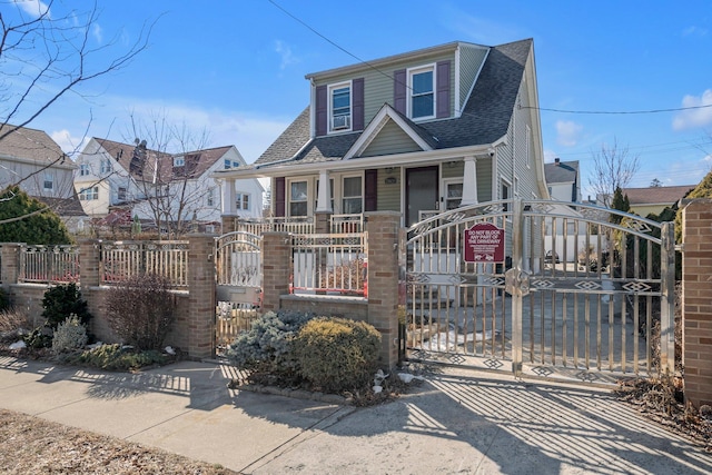 view of front of house with a fenced front yard, a residential view, a gate, and a shingled roof