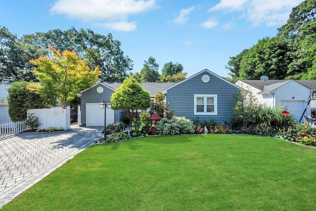 ranch-style home with a front lawn, decorative driveway, an attached garage, and fence