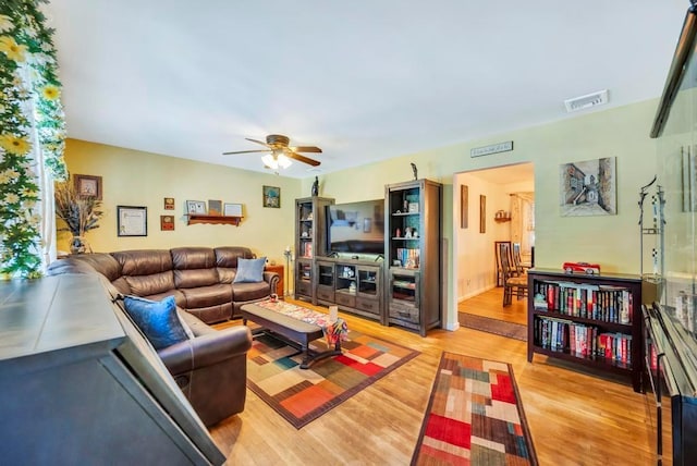 living room featuring visible vents, ceiling fan, and wood finished floors