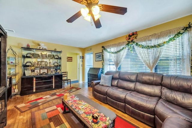 living area with a healthy amount of sunlight, ceiling fan, and wood finished floors