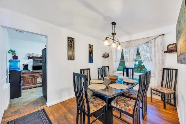 dining room with wood finished floors, visible vents, and baseboards