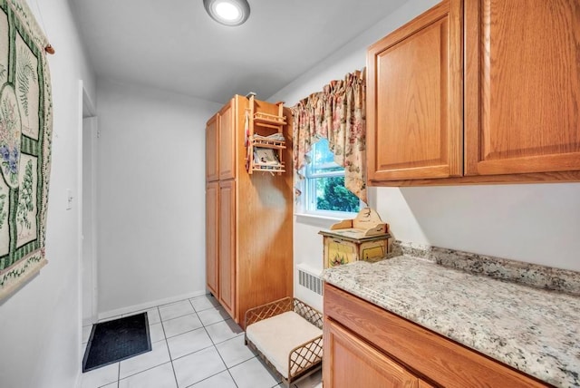 kitchen featuring light stone countertops, light tile patterned floors, and baseboards