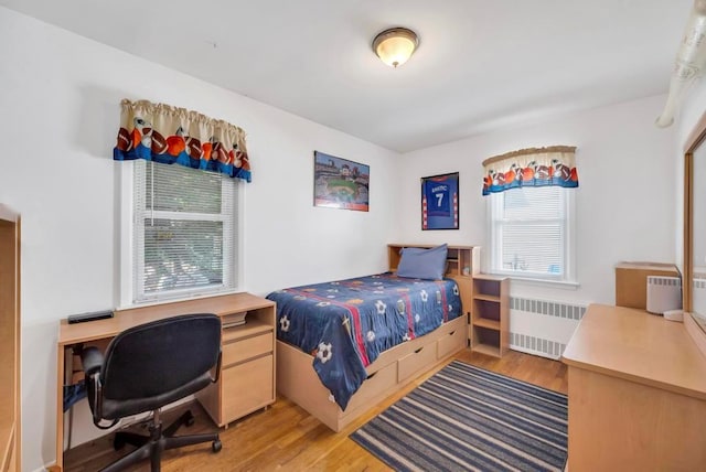 bedroom with light wood finished floors and radiator heating unit