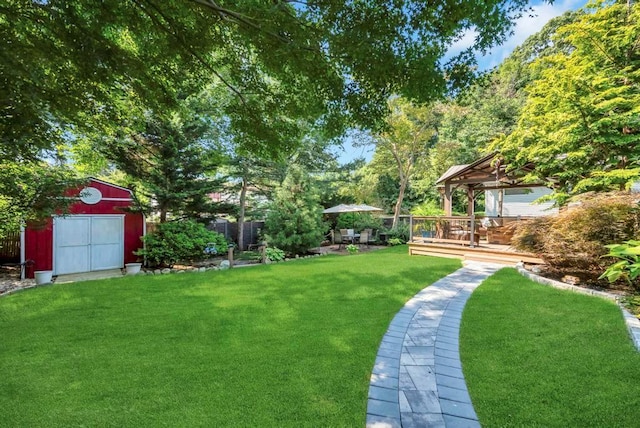 view of yard featuring an outbuilding, a storage shed, fence, a gazebo, and a wooden deck