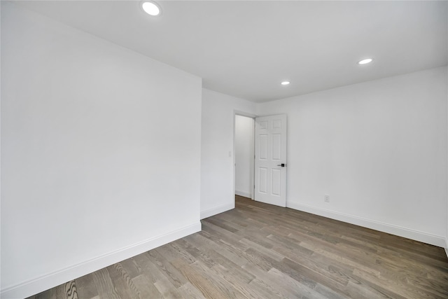 spare room with baseboards, wood finished floors, and recessed lighting