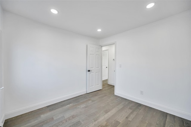 spare room with recessed lighting, wood finished floors, and baseboards