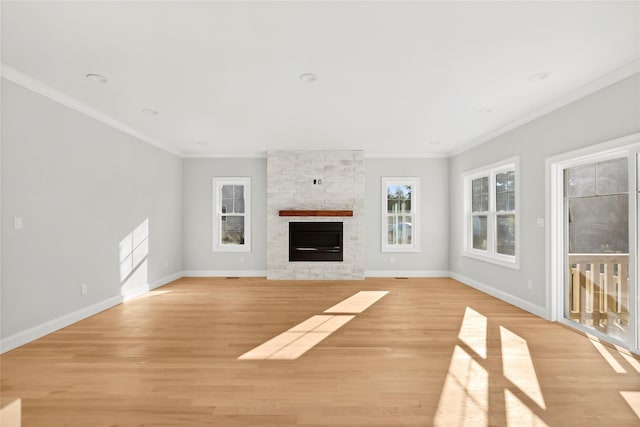 unfurnished living room with light wood-type flooring, ornamental molding, a fireplace, and baseboards