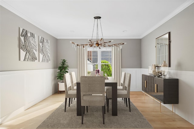 dining area with ornamental molding, a wainscoted wall, a notable chandelier, and light wood-style flooring