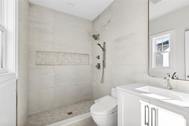 bathroom with toilet, tiled shower, and vanity