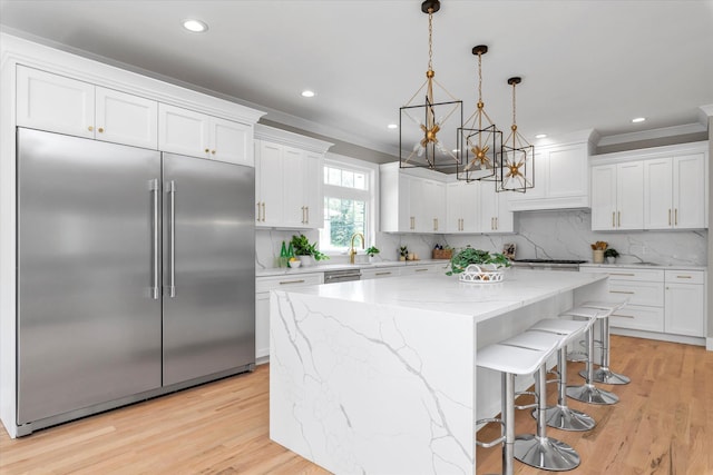18 Anita Ave, Syosset, NY 11791 - kitchen featuring stainless steel appliances, white cabinets, a chandelier, a center island, and ornamental molding