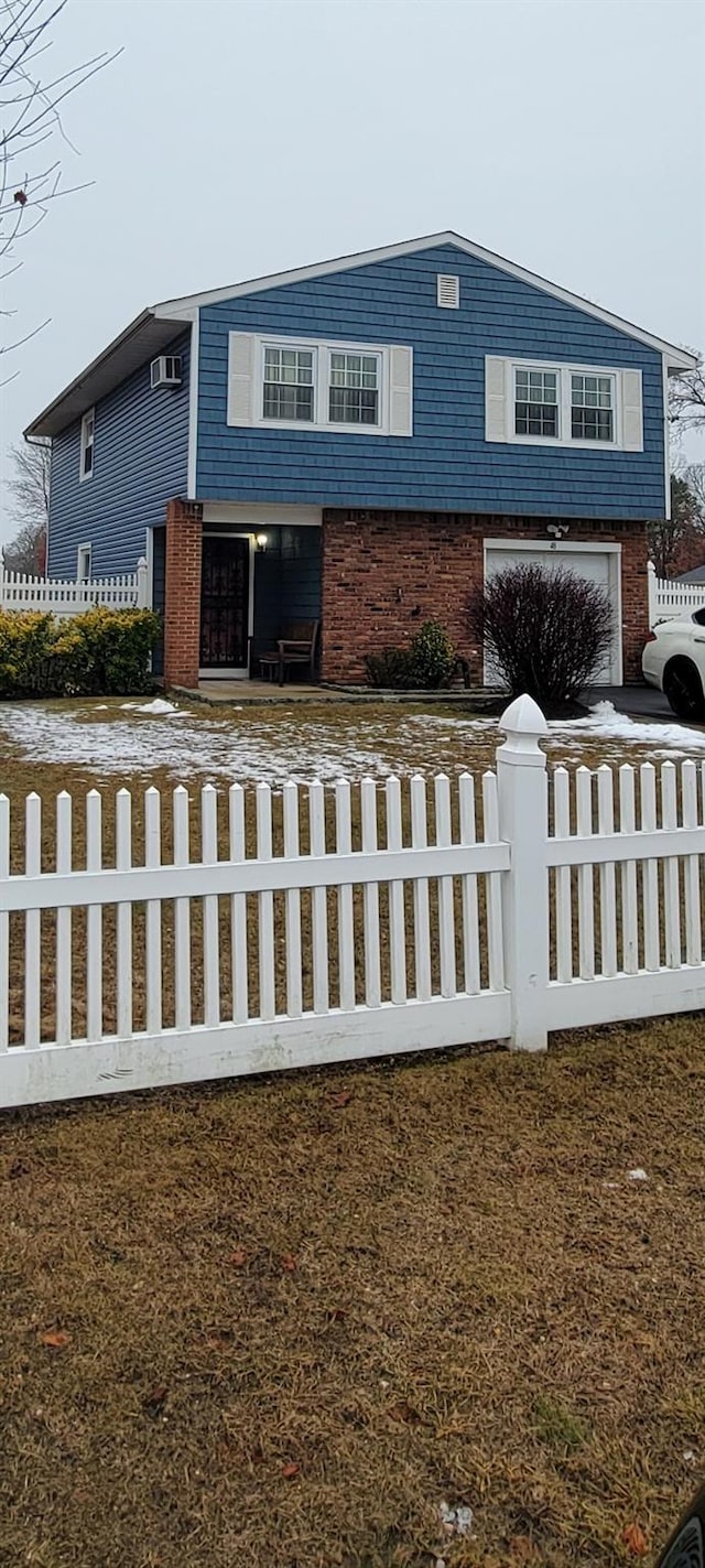 view of front of property featuring a garage, a fenced front yard, and brick siding