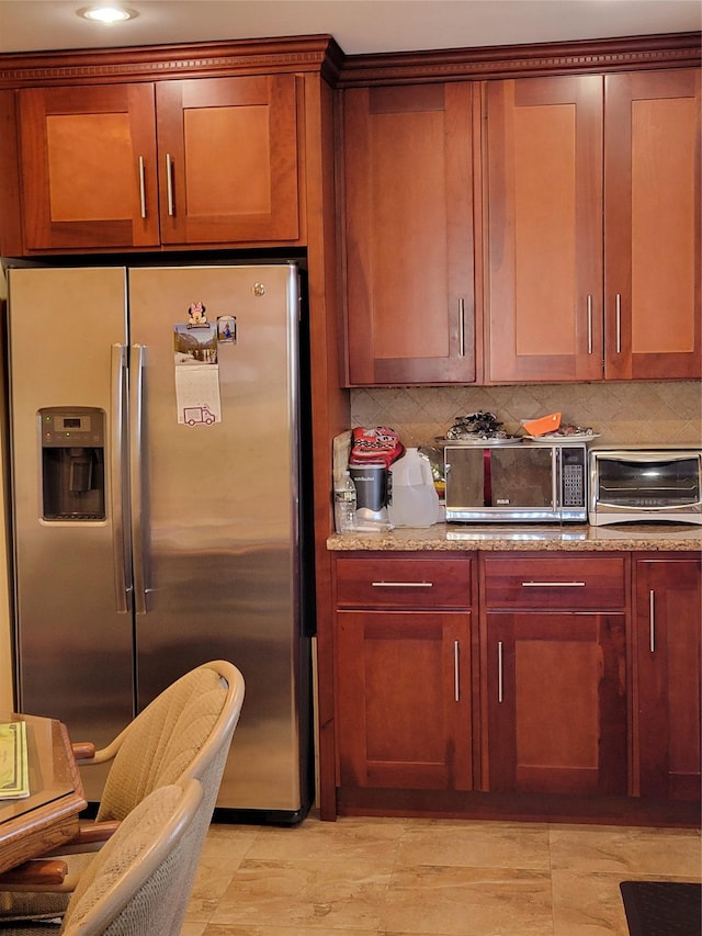 kitchen featuring light stone counters, stainless steel refrigerator with ice dispenser, decorative backsplash, and a toaster