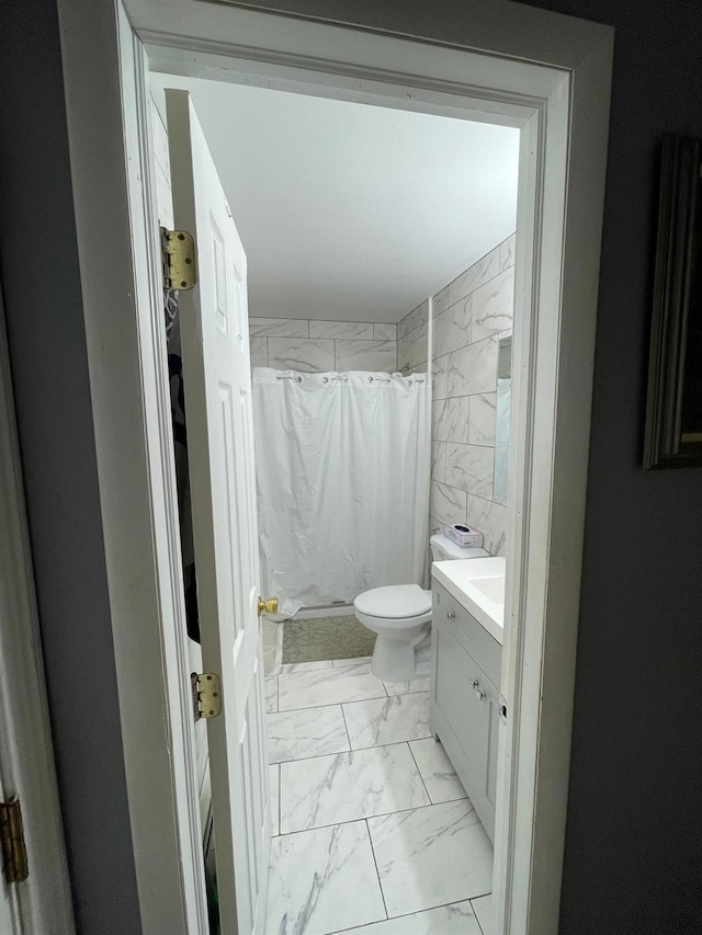 bathroom featuring marble finish floor, tile walls, curtained shower, toilet, and vanity