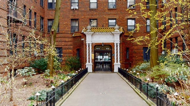 property entrance with fence, french doors, and brick siding