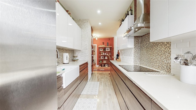 kitchen with light countertops, ventilation hood, stainless steel fridge, and white cabinets