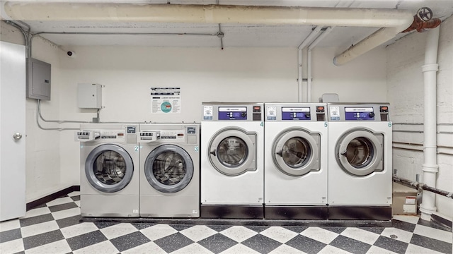 common laundry area featuring dark floors, washing machine and dryer, and electric panel