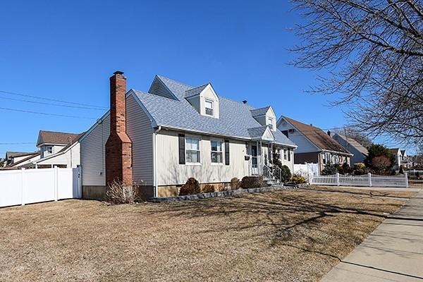 view of front facade with a shingled roof, fence, and a chimney