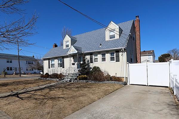 cape cod-style house with a gate, roof with shingles, fence, and a chimney