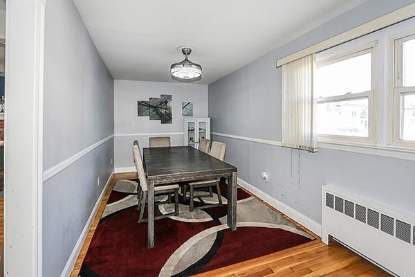 dining space featuring radiator heating unit, wood finished floors, and baseboards