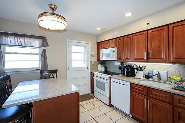 kitchen with a healthy amount of sunlight, white appliances, light stone counters, and a sink