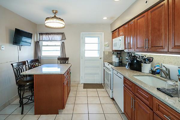 kitchen with white appliances, a breakfast bar area, a sink, and light tile patterned flooring