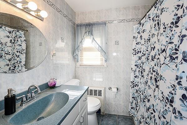 full bathroom with toilet, vanity, tile walls, and tile patterned floors