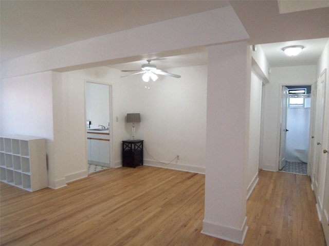 empty room with light wood finished floors, ceiling fan, baseboards, and a sink