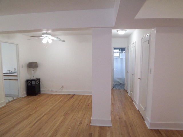 spare room featuring baseboards, a ceiling fan, and light wood finished floors