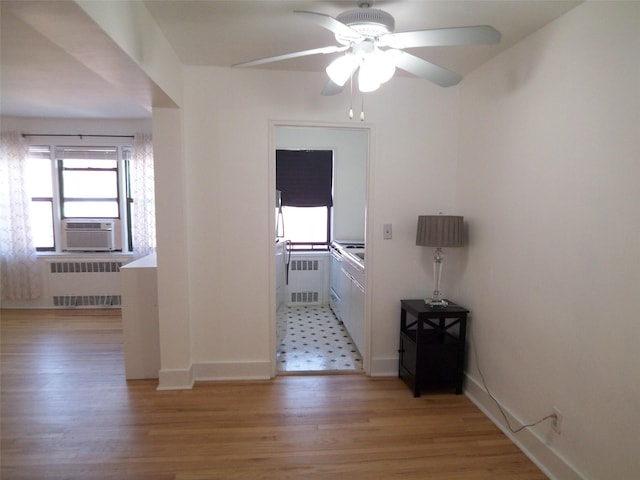 corridor featuring radiator heating unit, baseboards, light wood-type flooring, and cooling unit