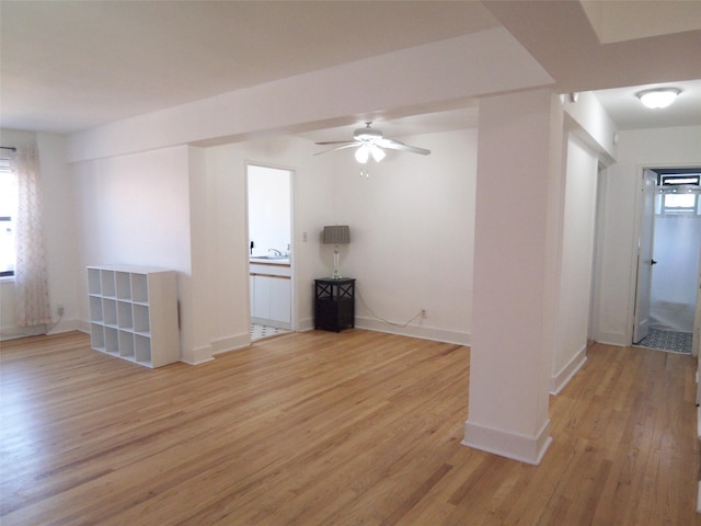 unfurnished living room featuring a sink, baseboards, light wood-style floors, and ceiling fan