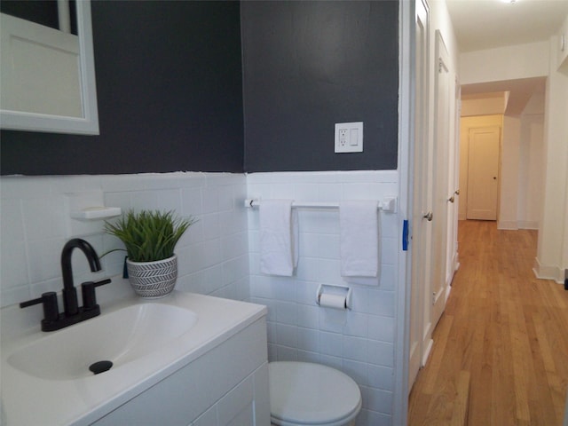 bathroom with vanity, wood finished floors, wainscoting, tile walls, and toilet