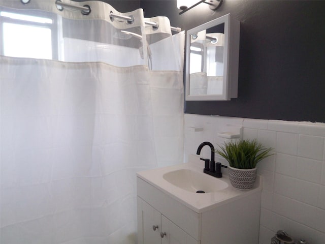 bathroom featuring curtained shower, tile walls, and vanity